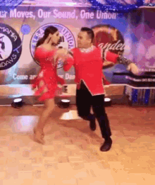 a man and woman are dancing on a dance floor in front of a sign that says " our moves our sound one union " .