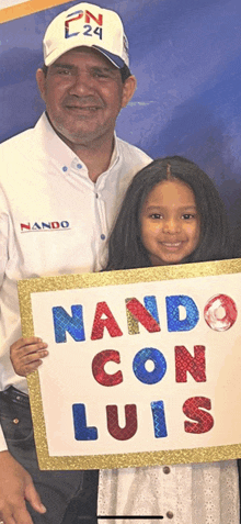 a little girl holding a sign that says ' nando con luis '