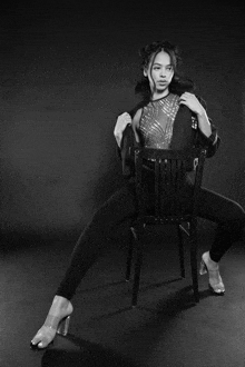 a black and white photo of a woman sitting on a chair with her legs crossed