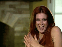 a woman with long red hair is smiling and clapping