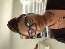 a woman wearing glasses and a necklace is standing in front of a bookshelf with the odyssey on it