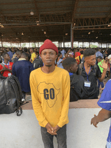 a man wearing a yellow shirt that says go stands in a crowd