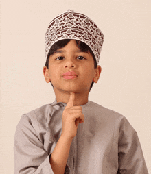 a young boy wearing a gray shirt and a brown and white hat