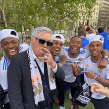 a man wearing a scarf that says fly emirates is surrounded by other people