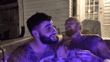 a man with a tattoo on his arm is laughing with another man