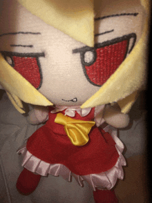 a stuffed doll with a red dress and yellow bow