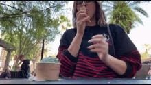 a woman sitting at a table eating ice cream from a cup that says ' ice cream ' on it