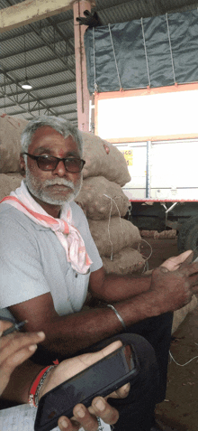 a man with glasses and a scarf around his neck is sitting in front of bags