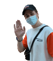 a man wearing a face mask and a hat waves his hand