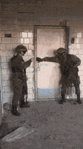 two soldiers are standing in front of a door and one of them is holding a gun