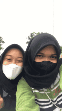 two girls wearing face masks pose for a photo