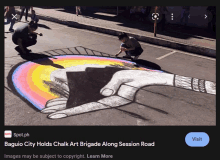 two people are drawing a rainbow with chalk on a street