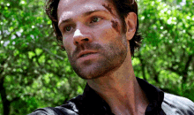 a close up of a man 's face with a black shirt and a beard