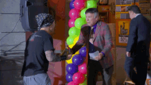 a man in a suit stands in front of a balloon display with a sign that says 50 % off