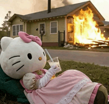 a stuffed hello kitty sitting in front of a house on fire