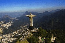 a large statue of jesus is surrounded by mountains and a city