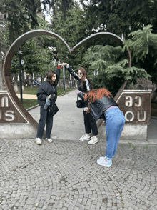 a group of girls pose in front of a heart shaped sculpture that says i love you