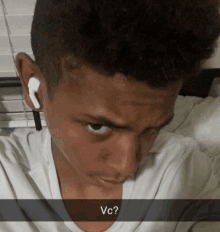 a boy wearing white ear buds has the word vc written on the bottom