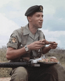 a soldier in a black beret is eating a piece of meat while holding a gun .