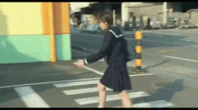 a girl in a school uniform is walking across a street .