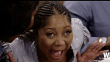 a woman with braids is making a funny face while being kissed by a man .