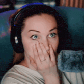 a woman is wearing headphones and covering her face with her hand .