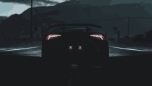 a black sports car is driving down a dark road