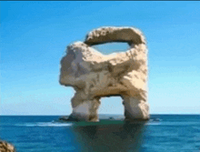 a large rock in the middle of the ocean with a hole in the middle .