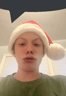 a young man wearing a santa hat makes a sad face