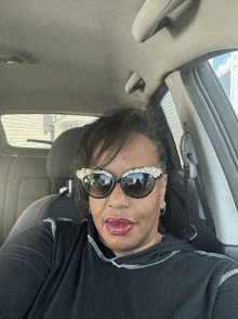 a woman wearing sunglasses and a black shirt is sitting in a car