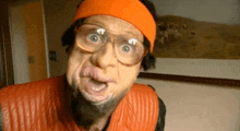 a man wearing glasses and a headband is making a funny face .