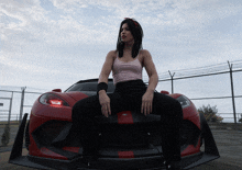 a woman with dreadlocks sits on the front of a red car