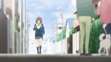 a girl in a school uniform is walking down a street with a black cat