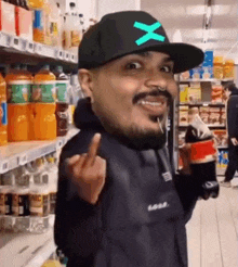 a man wearing a hat with the letter x on it is giving the middle finger in a supermarket .