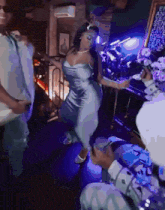 a woman in a blue dress is dancing in a room with purple lights
