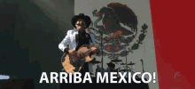 a man playing a guitar in front of a mexican flag with the words " arriba mexico " on the bottom