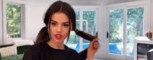 a woman with red lipstick is holding a curling iron in her hand