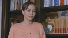 a woman in a pink shirt is smiling in front of a bookshelf that has a book titled doctor on it