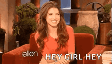 a woman in a red shirt is sitting in a chair and smiling while talking to ellen degeneres .