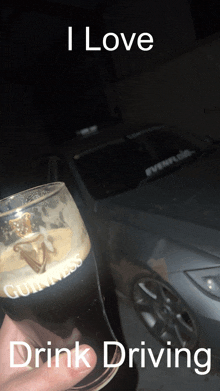 someone holding a glass of guinness in front of a car that says i love drink driving