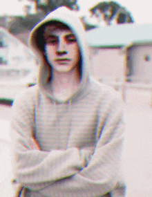 a blurry picture of a boy wearing a hoodie with his arms crossed