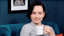 a woman is sitting on a couch holding a mug of coffee .