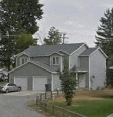 a large gray house with two garages and a car parked in front of it