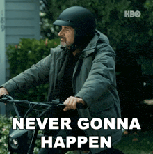 a man wearing a helmet is riding a motorcycle with the words " never gonna happen " above him