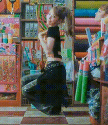 a woman in a black crop top is kneeling down in front of a store