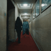 a woman in a suit walks down a hallway with a hbo logo on the wall behind her