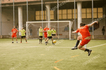 a man in a red shirt is kicking a soccer ball while others watch