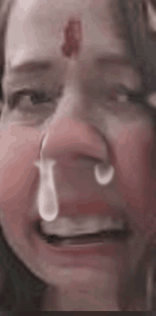 a close up of a person 's face with a tear coming out of their nose .