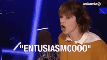 a woman wearing headphones is screaming into a microphone and says " entusiasmoooo " .