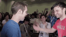 a man in a red shirt that says ' woolfie ' on it stands in front of a crowd of people